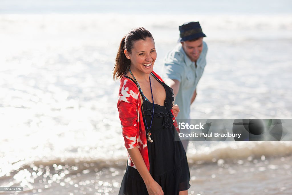 Coppia giocando in onde sulla spiaggia - Foto stock royalty-free di 25-29 anni