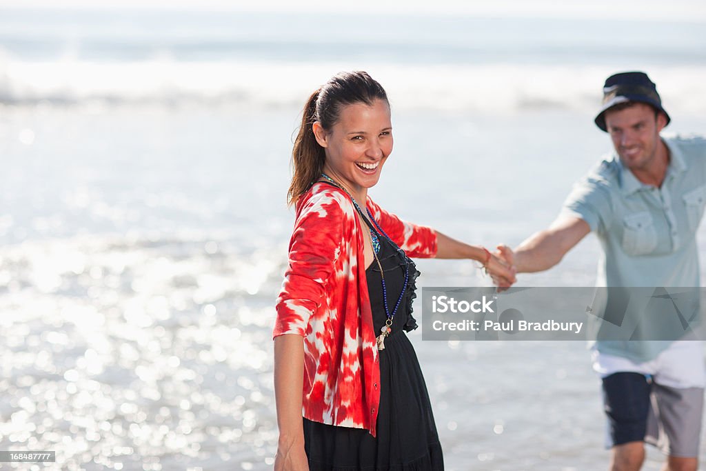 Couple playing in waves on beach  25-29 Years Stock Photo