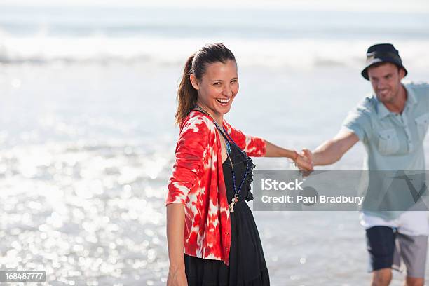 Couple Playing In Waves On Beach Stock Photo - Download Image Now - 25-29 Years, 30-34 Years, 30-39 Years