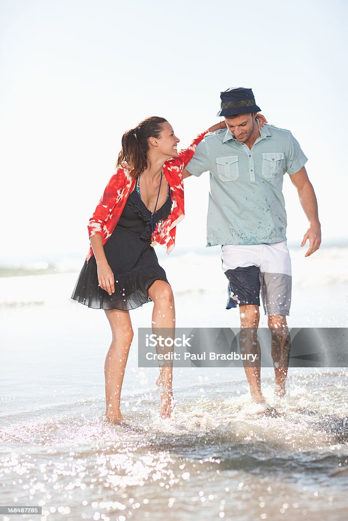 Pareja jugando en las olas en la playa - Foto de stock de 25-29 años libre de derechos