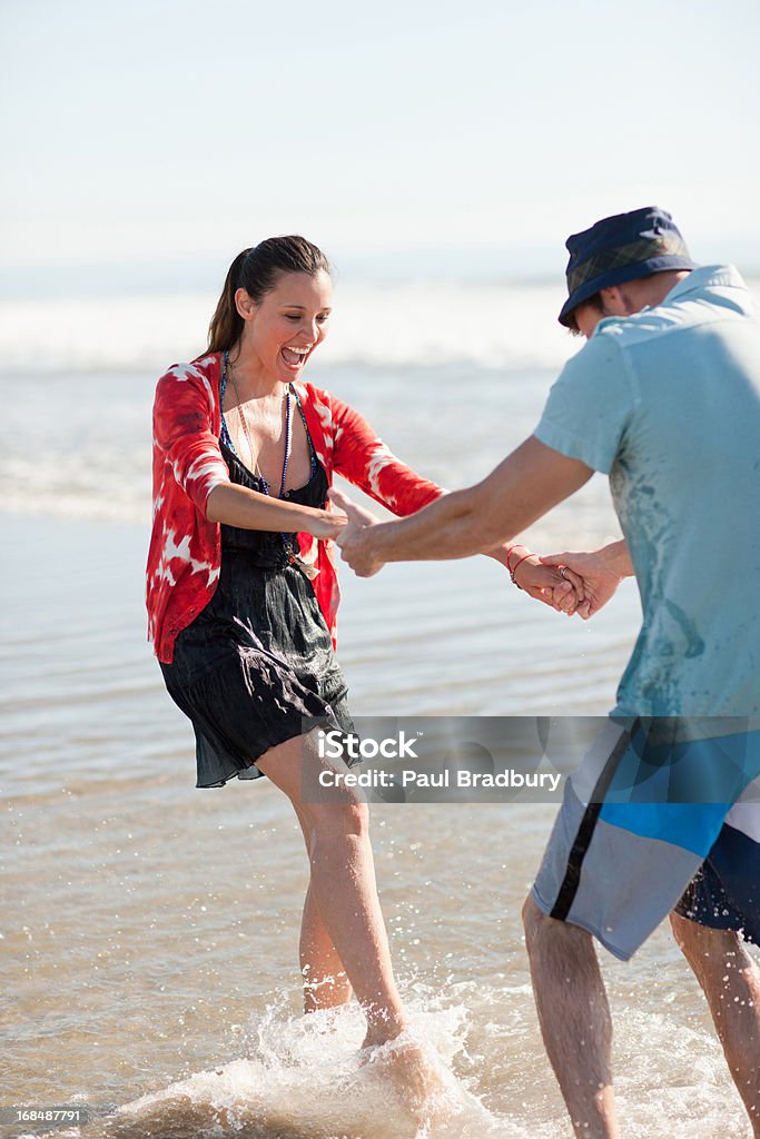 Pareja jugando en las olas en la playa - Foto de stock de 25-29 años libre de derechos