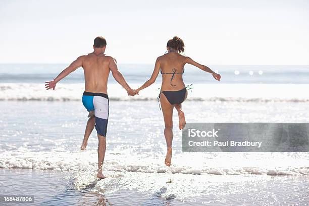 Casal Brincando Nas Ondas Na Praia - Fotografias de stock e mais imagens de Chapinhar - Chapinhar, Mar, Praia