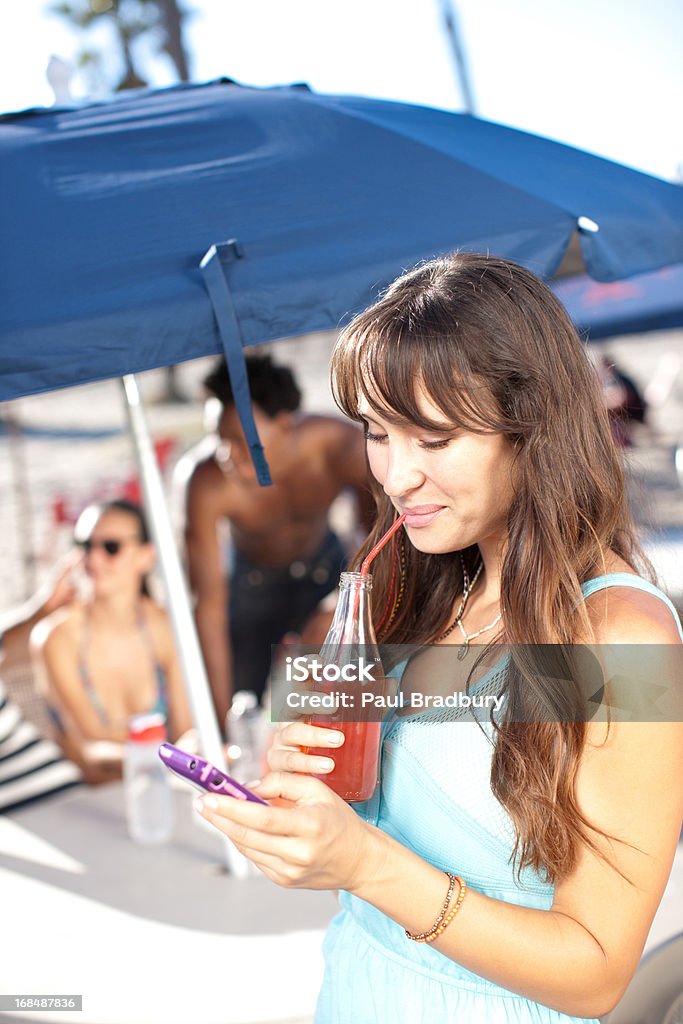Femme avec un jus de fruits à l'aide de téléphone portable à l'extérieur - Photo de 20-24 ans libre de droits