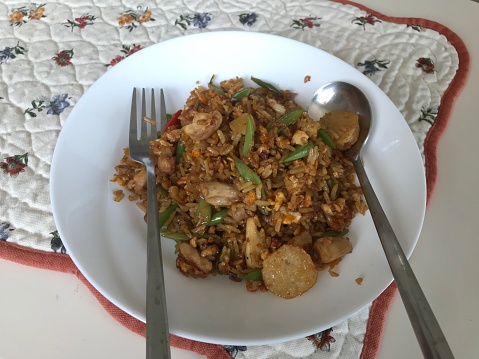 Nasi Goreng with a spoon and fork ready to eat with eggs, chicken, meatballs, and vegetables. Indonesian food, Indonesian fried rice, home cook