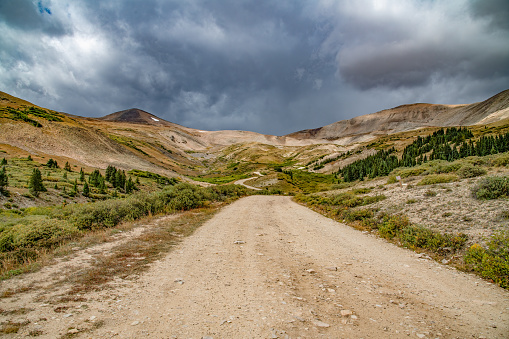 Rocky mountain dirt road at 12000 feet with autumn colors and thunderstorms near Fairplay, Colorado in central Colorado in western USA of North America. Nearby towns are Denver, Aspen, Vail, Breckenridge, Leadville and Colorado Springs, Colorado. Road through abandoned Gold mines and ghost towns.