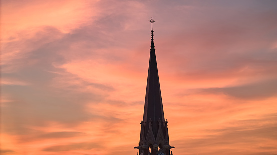 The silhouette of the cross and church bell tower in sunrise, sunset time. Drone shot. High quality photo