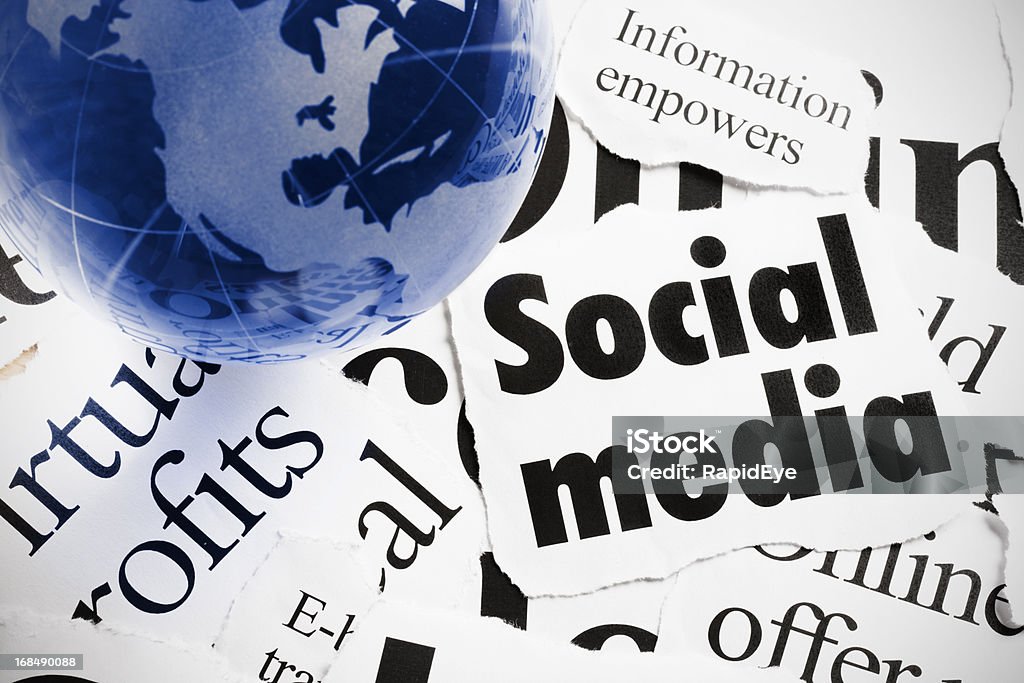 Blue glass globe paperweight on headlines about Internet's social media A blue glass globe-shaped paperweight rests on print headlines covering  the social media aspects of the Internet and their influence on business.  Alphabet Stock Photo