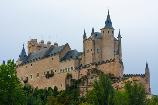 Segovia, Spain. September 15, 2022 -Alcazar of Segovia on the rocky hill with cliffs, from a praire in the valley