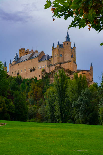 Alcazar of Segovia from the valley Segovia, Spain. September 15, 2022 -Alcazar of Segovia on the rocky hill with cliffs, from a praire in the valley el alcazar palace seville stock pictures, royalty-free photos & images