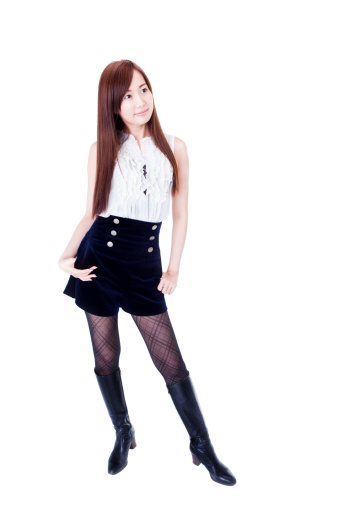 A beautiful young Japanese brunette standing against a white background in studio.