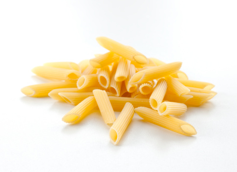 dry uncooked pasta tubes, penne, on white background