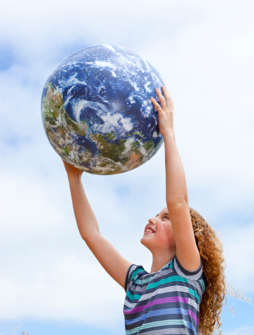 happy little girl holding earth ball up to the sky