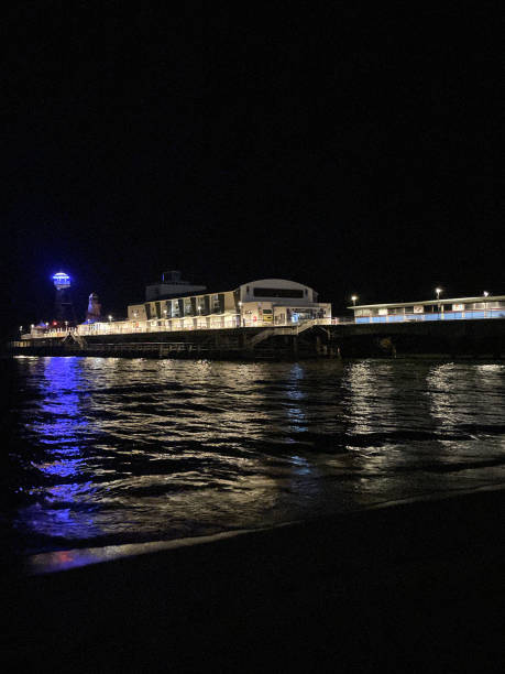 Stock photo showing night-time beachfront view of Bournemouth's seafront theatre on the illuminated pier.