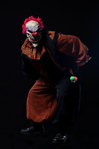 Man in scary clown Halloween costume on black. Copy space. CLICK FOR SIMILAR IMAGES AND LIGHTBOX WITH MORE SEASONAL IMAGES.