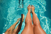 tanned legs against the background of clear water in the pool. summer vacation under the sun. background for the design