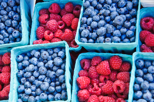 Blue paperboard pint baskets holding ripe blueberries and raspberries at a farmers market on Cape Cod