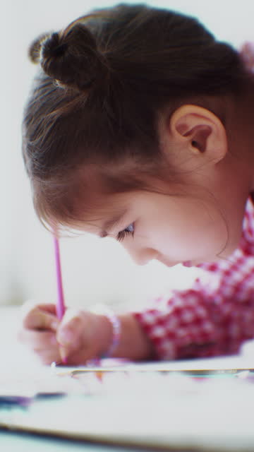 Little girl enjoys drawing and coloring on paper