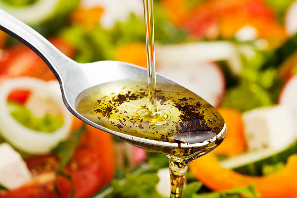 Salad Dressing. Olive oil pouring over salad. infused oil stock pictures, royalty-free photos & images