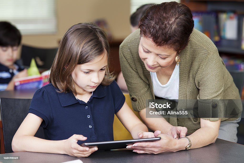 Librarian helping elementary student with project on digital tablet Librarian helping 9-year old girl with project on digital tablet (Sacto'lypse 2012) You might also be interested in these: Serious Stock Photo