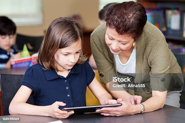 Librarian Helping Elementary Student With Project On Digital Tablet Stock Photo - Download Image Now