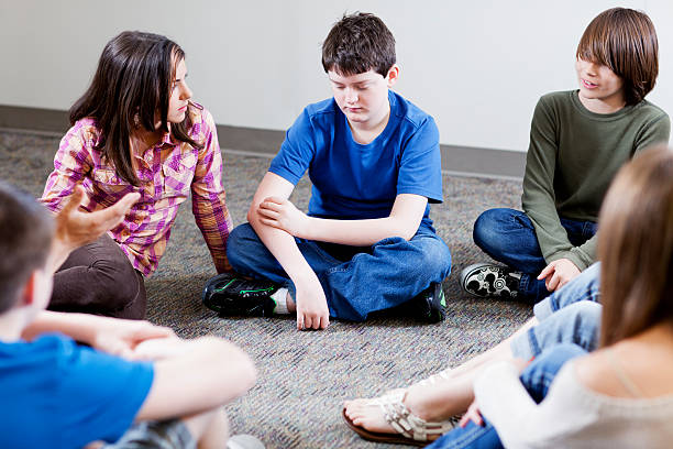 grupo de jovens adolescentes segurando discussão em um círculo - sentar se pose - fotografias e filmes do acervo