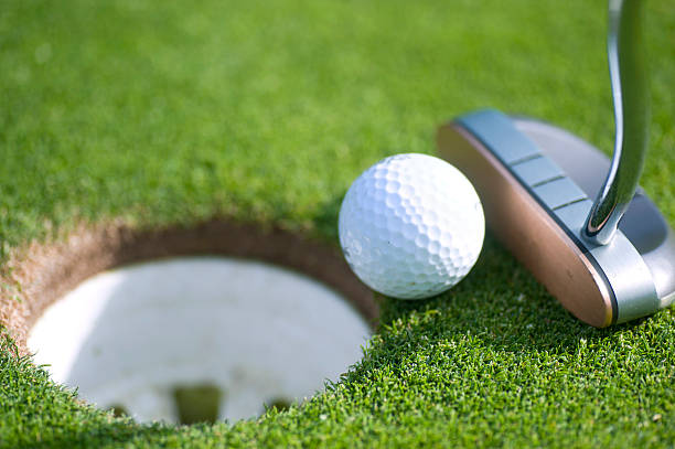 istock golfball next to hole with putter on puttinggreen 168498483