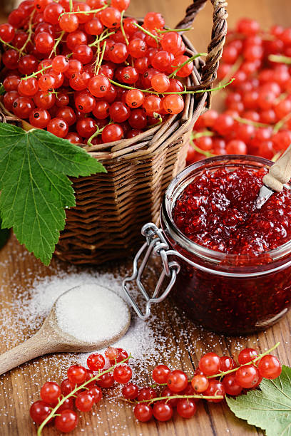 Basket of red currant and jam jar with spoon stock photo