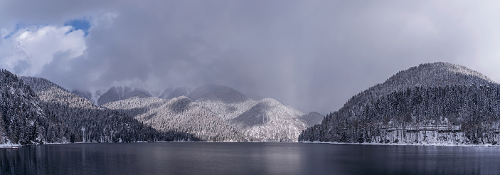 Beautiful winter panorama with mountain Ritsa lake and snow-covered trees along the shore. Great natural background with copy space for your design.