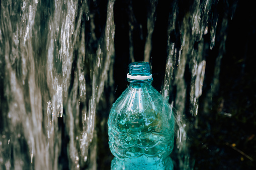 The flow of water from the waterfall fills the bottle