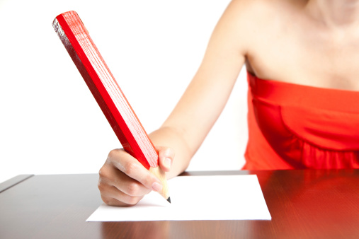 Girl in red dress writing with huge red pencil