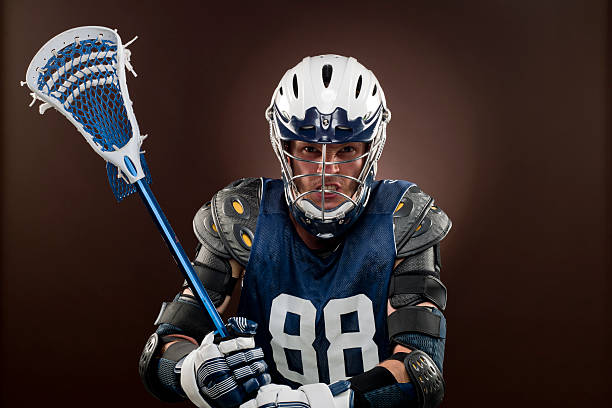 Lacross player, XXXL image head and shouders shot of a Lacross player holding Lacross stick looking at the camera on brown background Chest Protector stock pictures, royalty-free photos & images