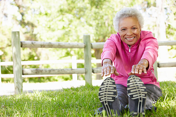 Close up of a senior woman stretching in the park  Senior African American Woman Exercising In Park Stretching To Tough Her Toes touching toes stock pictures, royalty-free photos & images