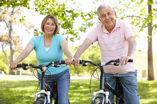 Senior Hispanic Couple Sitting On Bikes In Park