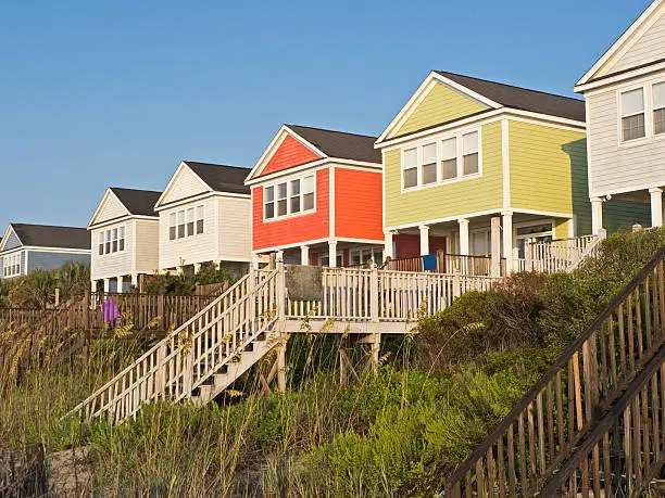 A summer scene on the beach with cottages in a line.