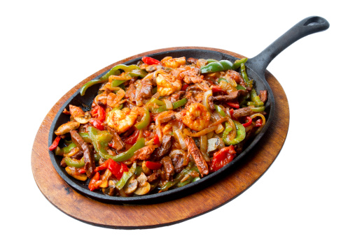 Shrimp, Beef and Chicken Fajitas on a hot skillet with onions, peppers and mushrooms