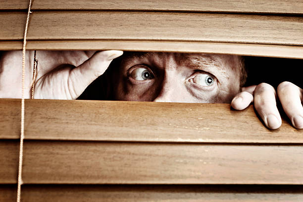 istock Worried-looking man peeps sideways through venetian blind 168505442