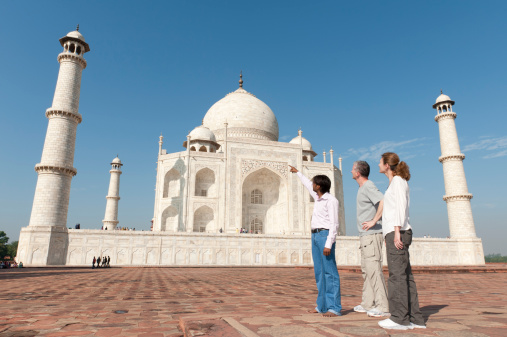 Local Indian male guide describes the beauty and architecture of the Taj Mahal to a western tourist couple travelling in India.