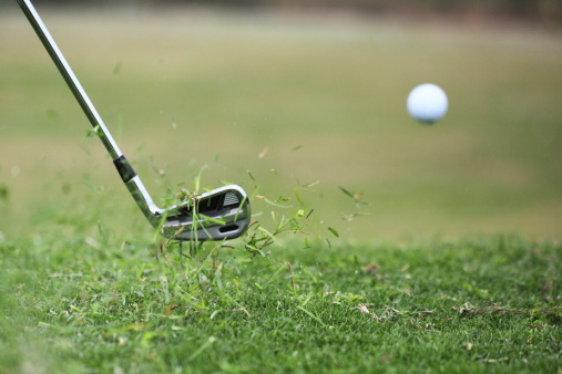 Golf club hits ball in the air, with grass flying. Extremely fast shutter speed.