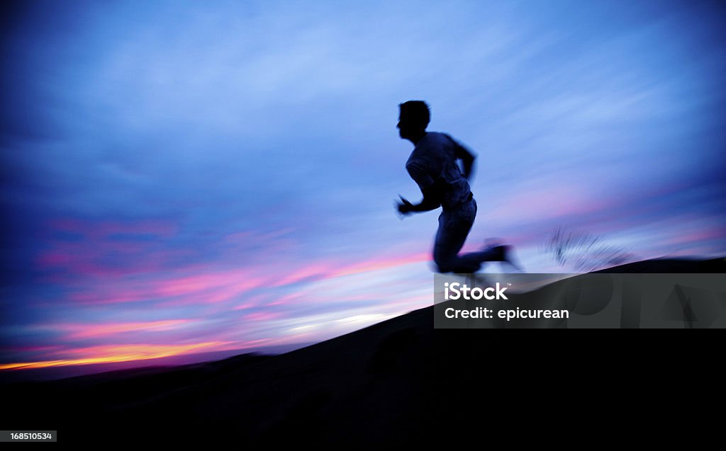 Solitario Figura corriendo a través del desierto al atardecer - Foto de stock de Correr libre de derechos