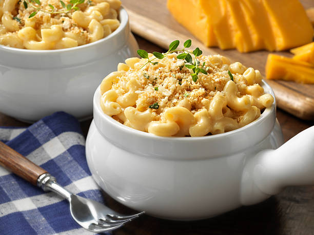 Macaroni and cheese in a white bowl on blue plaid tablecloth stock photo