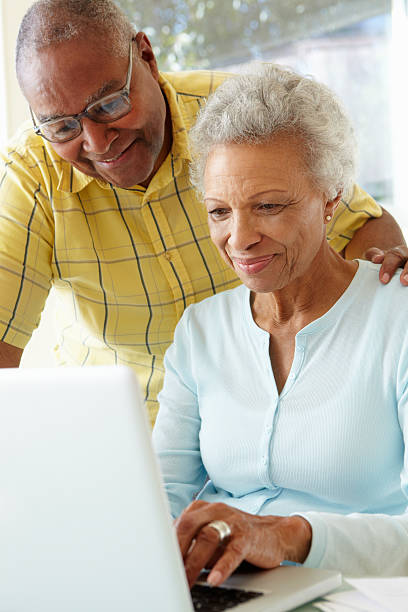 casal idoso usando computador portátil em casa - senior adult happiness computer looking at camera imagens e fotografias de stock