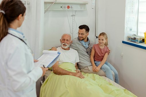 Hospital Ward: Female Doctor Talking to a Senior Patient His Son and Granddaughter in Modern Hospital