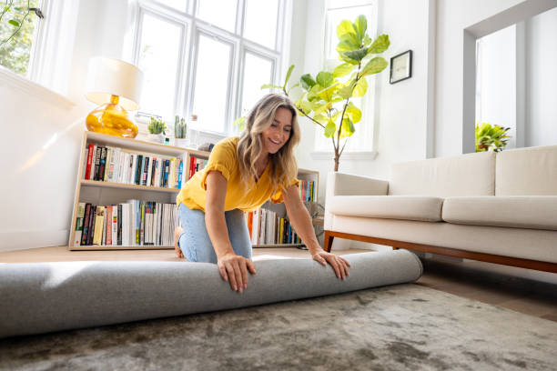 istock Happy woman moving house and unrolling a carpet while unpacking 1685138093