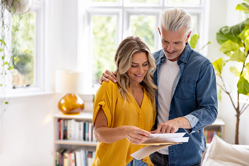 Happy Caucasian couple checking their mail at home and smiling - domestic life concepts