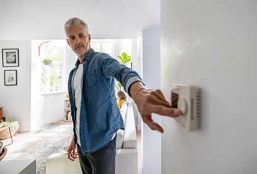 Caucasian man adjusting the temperature of his house with a dimmer - lifestyle concepts