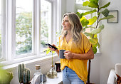 Woman at home using her cell phone while drinking coffee