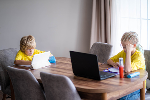 Distance learning online education, boy and girl studying at home with digital tablet and laptop, doing school homework, Training books and notebooks on table