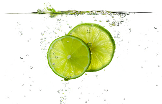 Lime splash slices falling in water.