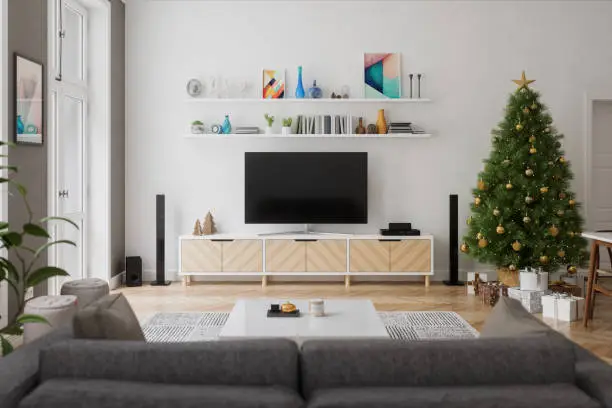 A cozy living room decorated for Christmas, featuring a tree, a couch, and a TV.