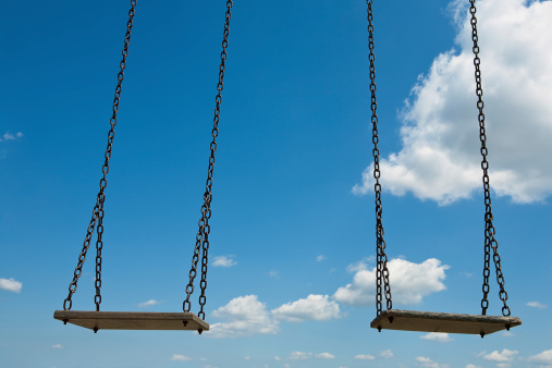 Two empty swings against blue summer sky
